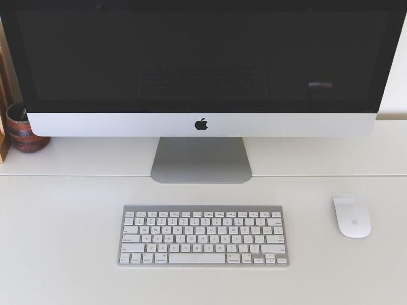 An iMac desktop computer with keyboard and mouse on a white desk