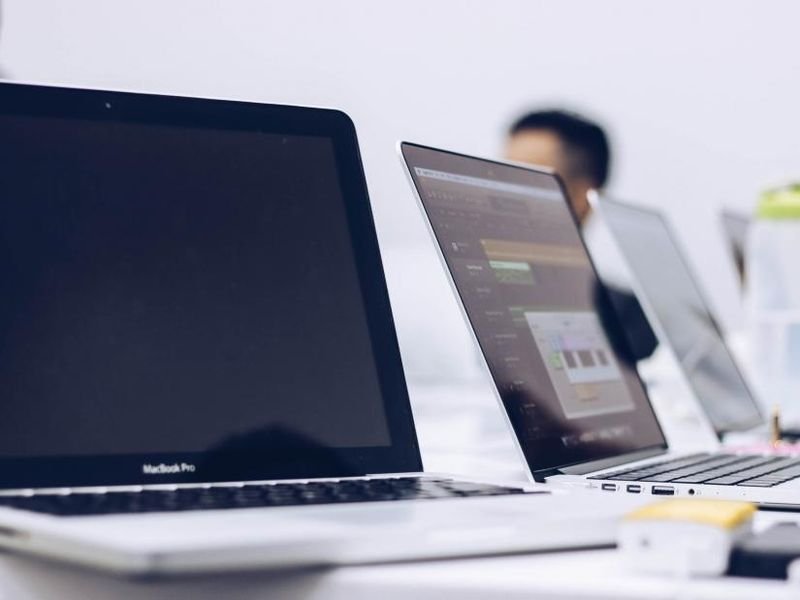 MacBook laptops open on a bright white desk