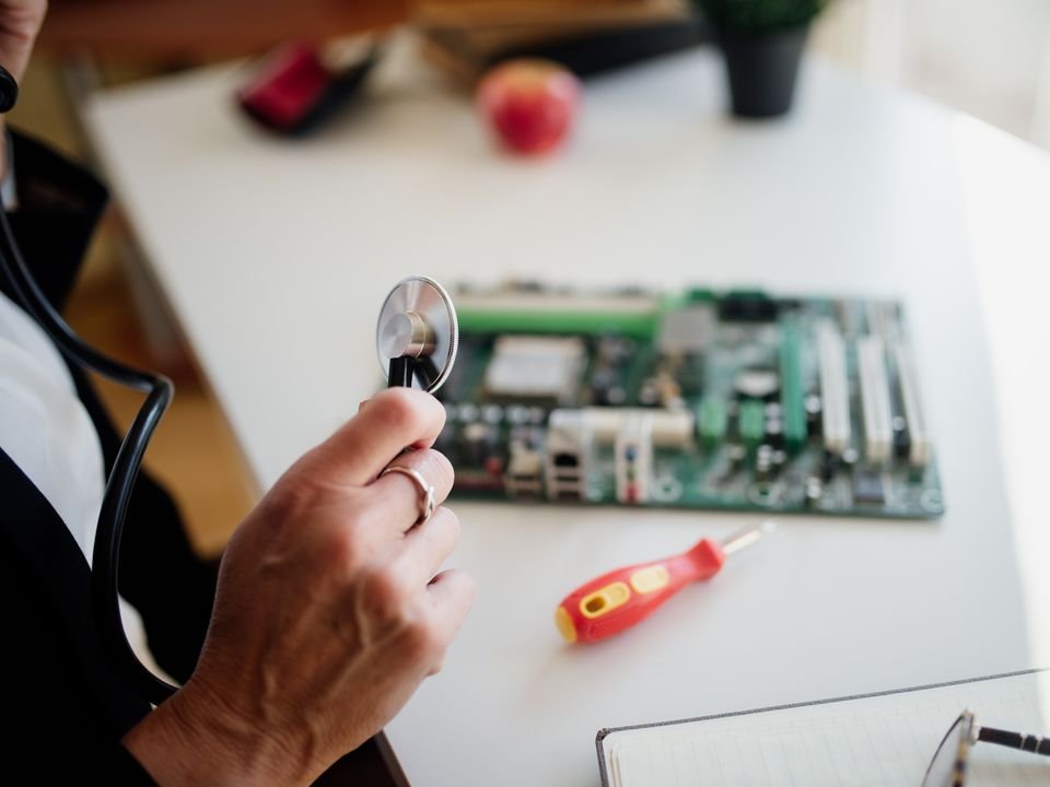 A technician checking a computer circuit board on a white workbench
