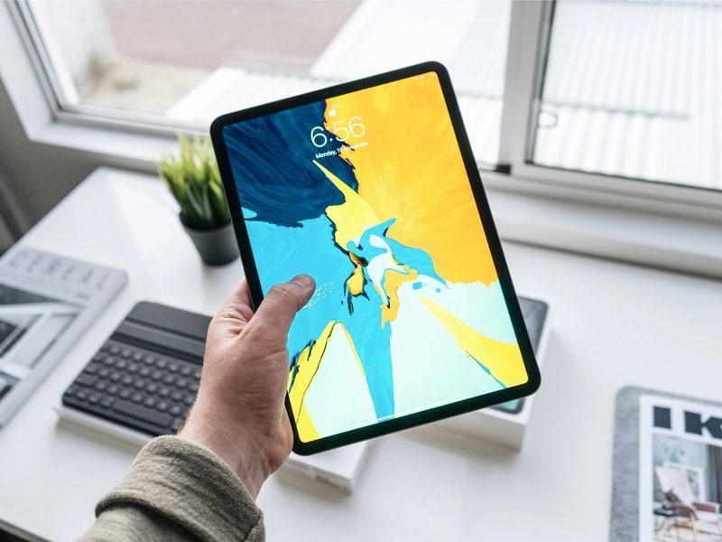 A hand holding an iPad with a bright screen