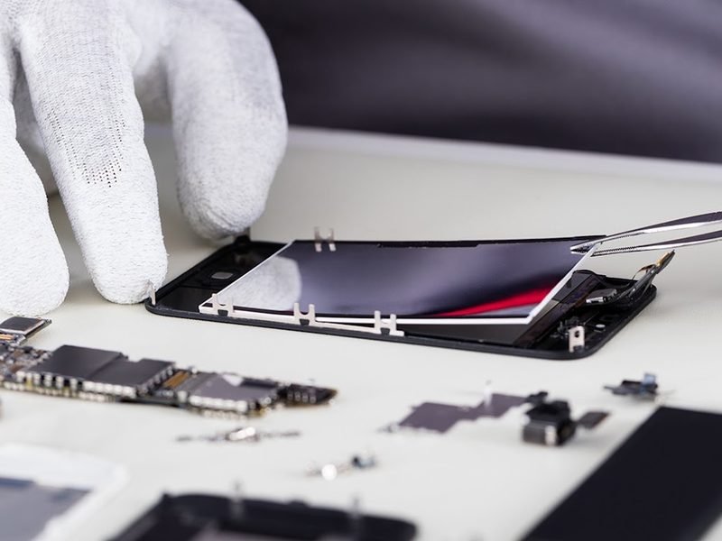 A technician replacing a smartphone screen with precision tools