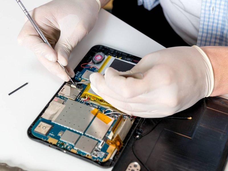 A technician working on the circuit board inside an opened tablet